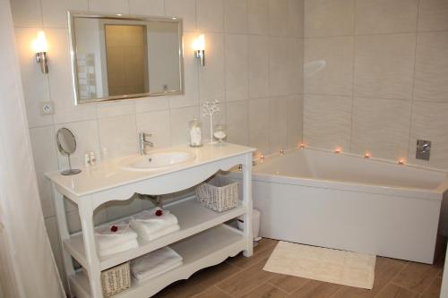 a bathroom with a tub and a sink and a mirror at Au Coeur Des Hôtes in Steenvoorde