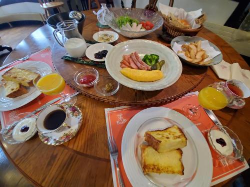 a wooden table with plates of food on it at プチホテル葡萄屋 in Hakuba