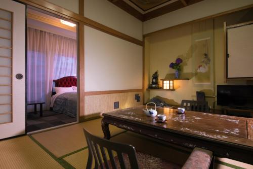 a living room with a table and a bedroom at Hotel Housenkaku in Beppu