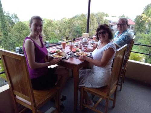 two women and a man sitting at a table with food at KARANG SARI Guesthouse & Warung in Munduk