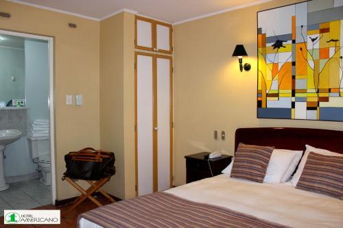 Un dormitorio con una cama y un cuadro en la pared. en Hotel Americano, en Arica