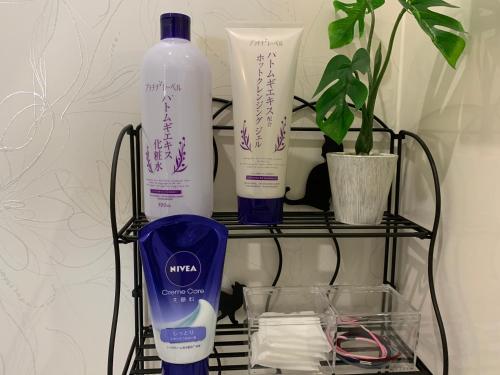 a rack with two bottles of sunscreen and a bottle of water at GUEST HOUSE APPLE in Osaka