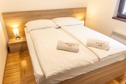 a bed with white sheets and two pillows on it at Apartments Mikic Zlatibor in Zlatibor