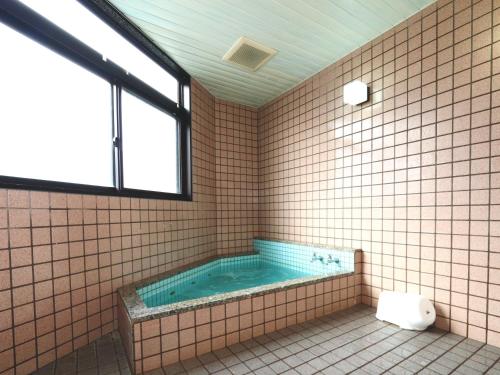 a bathroom with a tub with a toilet and a window at Nanakuraso in Omachi