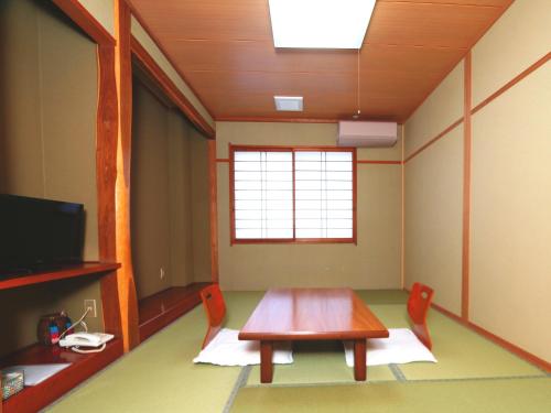 a room with a table and chairs and a television at Nanakuraso in Omachi