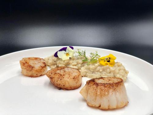 un plato de comida con risotto y flores. en Les Orchidées , Hôtel & Restaurant, en Verdún