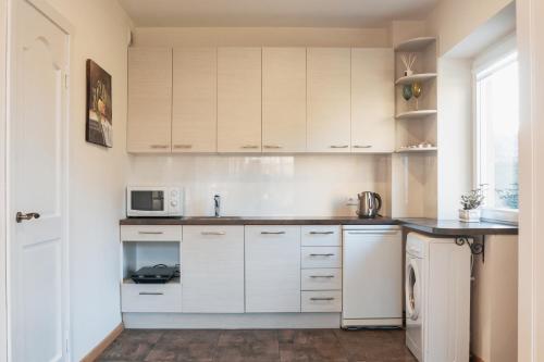 a kitchen with white cabinets and a microwave at Agnės svečių namai in Kaunas