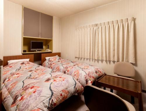 a bedroom with two beds and a desk and a window at Hotel Mimatsu in Nara