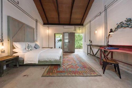 a bedroom with a bed and a desk in it at Mi Lugar Maldives in Nolhivaranfaru