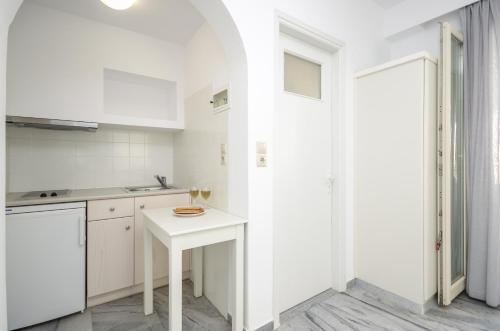 a kitchen with white cabinets and a white table at Soula Naxos in Naxos Chora
