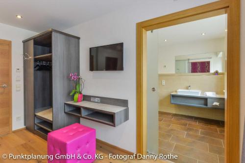 ein Badezimmer mit einem Waschbecken und einem rosa Stuhl in der Unterkunft Das Schwanstein in Schwangau