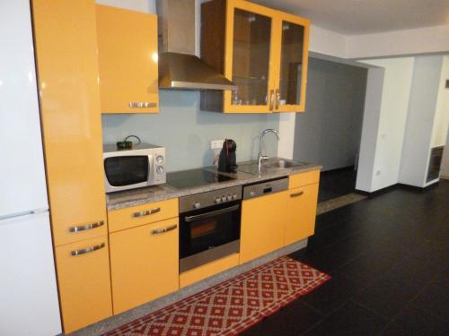 a kitchen with yellow cabinets and a microwave at Casa da Loja in Vieira do Minho