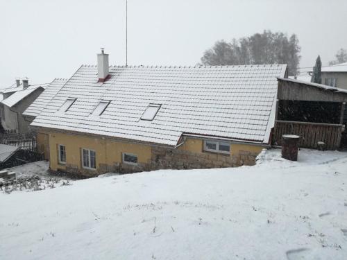 a yellow house with snow on the roof at MotoHostel Wolter - apartmán Leme in Všeň