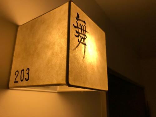 a light hanging from a wall with writing on it at Kamishichiken Oku in Kyoto