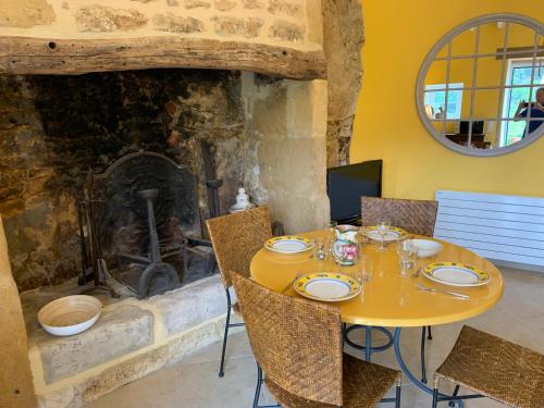 une table jaune avec des chaises devant une cheminée dans l'établissement Gîte chez le Gaulois, à Carsac-Aillac