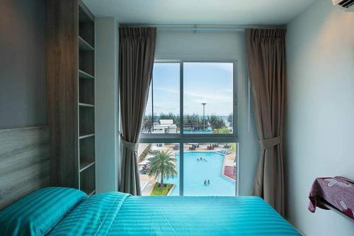 1 dormitorio con ventana y vistas a la piscina en GrandBlue Condominium Sea View, en Ban Tha Fat