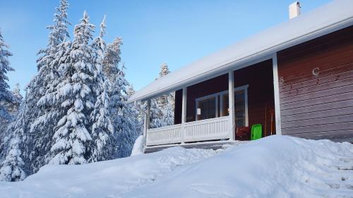 a house covered in snow next to some trees at Tilhi Chalet in Rovaniemi