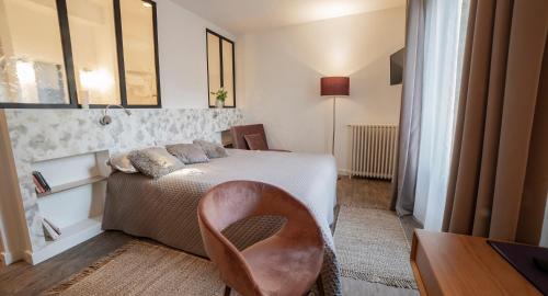 a bedroom with a bed and a desk and a chair at Les chambres de l'ATELIER à Montignac Lascaux in Montignac