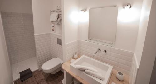 een witte badkamer met een wastafel en een toilet bij Les chambres de l'ATELIER à Montignac Lascaux in Montignac