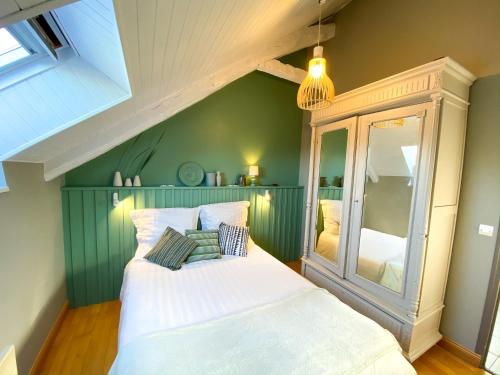 um quarto com uma cama branca e uma parede verde em Gîtes du Domaine du Grenier em Yffiniac