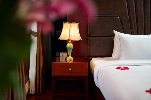 a bedroom with a bed and a lamp on a night stand at Dora Cruise by HAG in Ha Long
