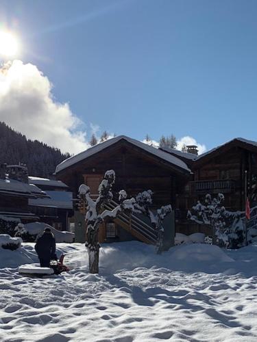 a snow covered house with a tree in the snow at Hotel de la Poste Verbier in Verbier