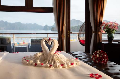 two swans made out of cream sitting on a bed at Dora Cruise by HAG in Ha Long