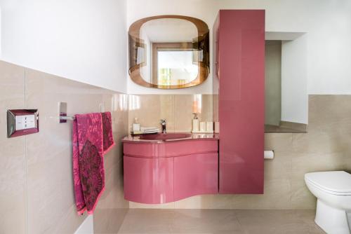 a bathroom with a pink sink and a mirror at La scala verde in Ragusa