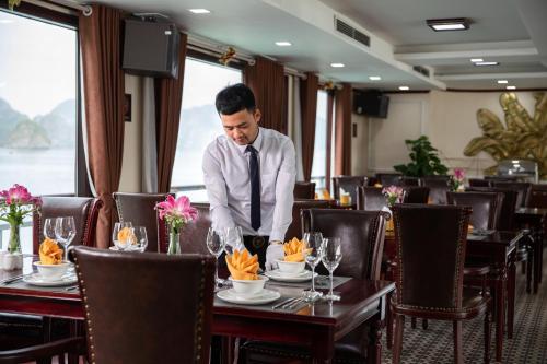 a man in a tie standing at a table in a restaurant at Dora Cruise by HAG in Ha Long