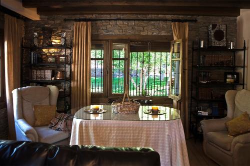 ein Wohnzimmer mit einem Tisch, Stühlen und einem Fenster in der Unterkunft La Noguera, lagunas de Ruidera in Ruidera