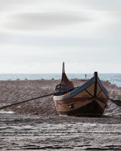 a boat sitting on the beach next to the ocean at Easy Stay In Espinho in Espinho