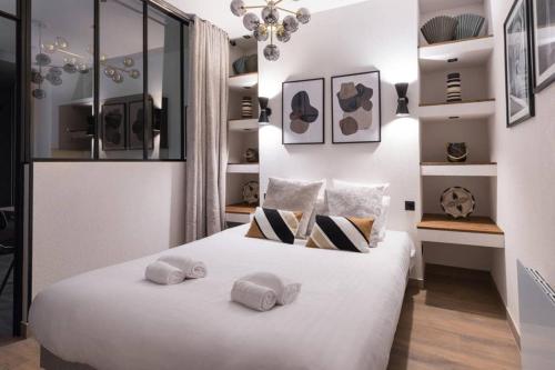 une chambre avec un lit blanc avec deux oreillers dessus dans l'établissement HSH Amsterdam St-Lazare Luxury & Design Apartment 6P-2BR, à Paris