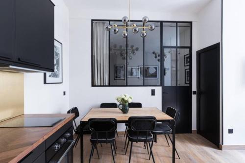 une salle à manger avec une table et des chaises noires dans l'établissement HSH Amsterdam St-Lazare Luxury & Design Apartment 6P-2BR, à Paris