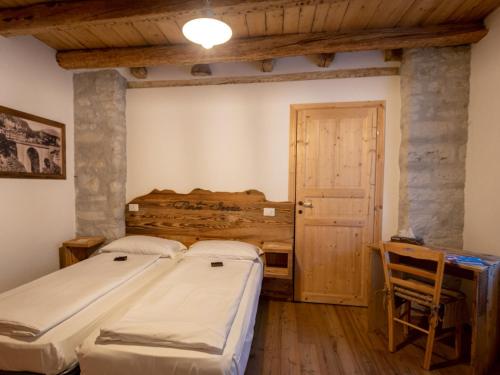 a bedroom with two beds and a table and a door at Locanda Ponte Serra in Lamon
