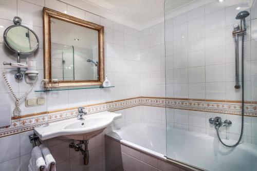 a bathroom with a sink and a tub and a mirror at Appartement Sport Steger in Saalbach-Hinterglemm