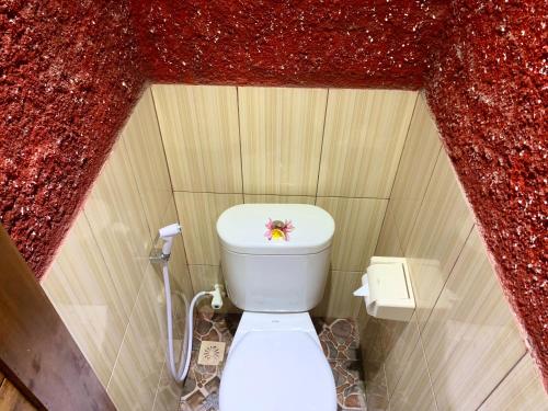 Baño pequeño con aseo en una pared roja en Nusa Garden Homestay, en Nusa Lembongan