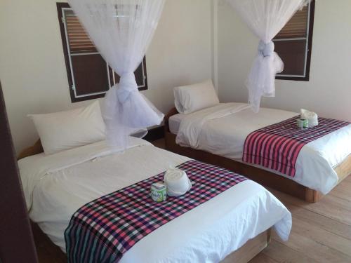 duas camas num quarto com lençóis brancos em Konglor Eco-Lodge Guesthouse and Restaurant em Ban O
