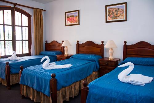 Una habitación con tres camas con cisnes. en El Cortijo Apart - Hotel en Merlo