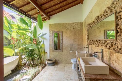 ein Badezimmer mit einer Badewanne, einem Waschbecken und einem Spiegel in der Unterkunft Sawah Villas in Ubud