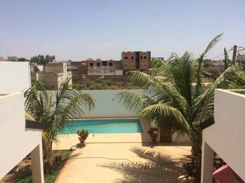a swimming pool with palm trees and buildings at SALY - Villa Kage 6 chambres -Clim-Wifi-Eau chaude-Billard-Babyfoot-Ping pong-Canal - ELECTRICITE NON COMPRISE in Sali Nianiaral