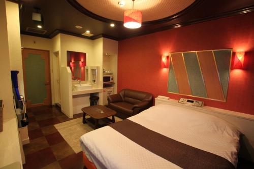 um quarto de hotel com uma cama e uma cadeira em Hotel Sindbad Hirosaki-Adult Only em Hirosaki