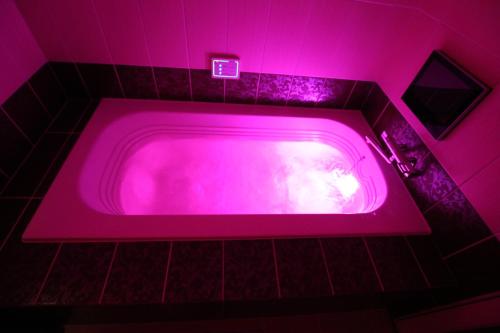 uma banheira rosa numa casa de banho com uma luz rosa em Hotel Sindbad Hirosaki-Adult Only em Hirosaki
