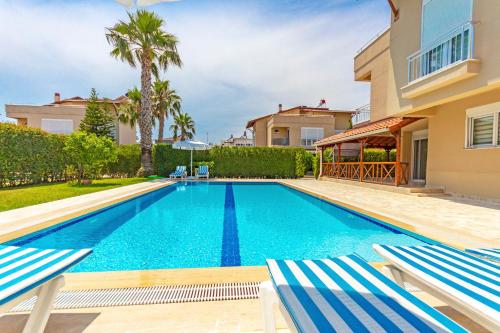 uma piscina numa villa com 2 espreguiçadeiras em Paradise Town Villa Alison 100 MBPS free wifi em Belek