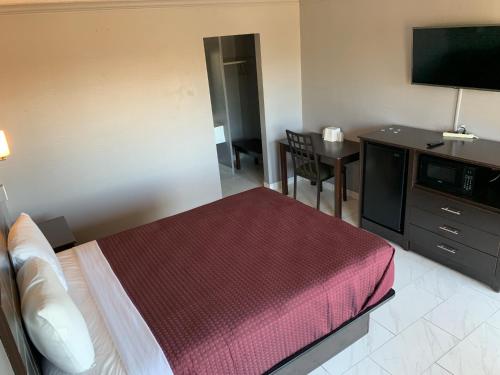ein Hotelzimmer mit einem Bett und einem Flachbild-TV in der Unterkunft Executive Inn & Suites Beeville in Beeville