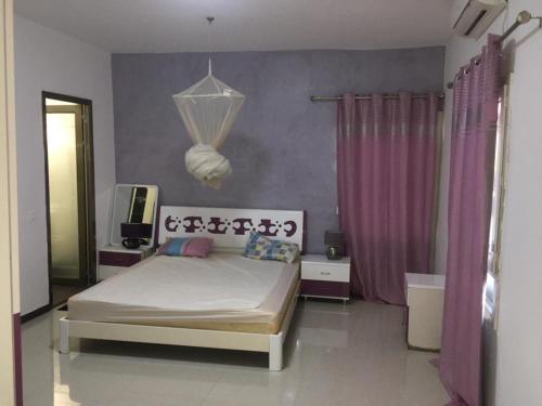 a bedroom with a bed and a purple wall at SALY - Villa Kage 6 chambres -Clim-Wifi-Eau chaude-Billard-Babyfoot-Ping pong-Canal - ELECTRICITE NON COMPRISE in Sali Nianiaral