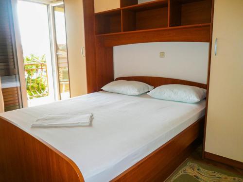 a bed with a wooden headboard and two pillows at Apartments Šarić in Makarska