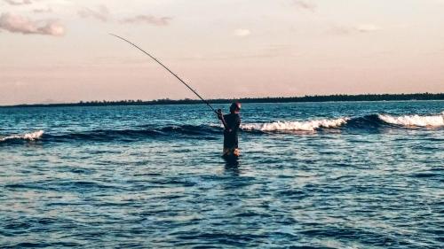 a man standing in the water fishing in the ocean at Pasikudah Eco Village Hotel in Pasikuda