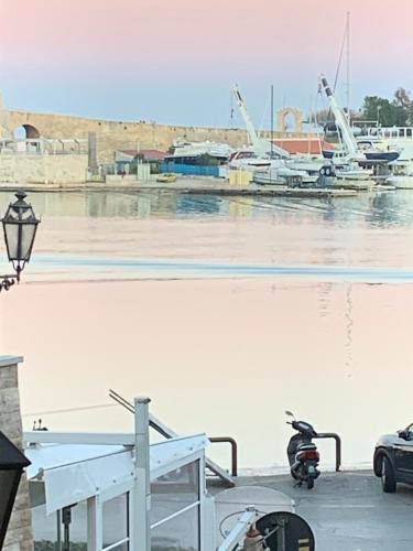 a motorcycle parked next to the water with a marina at La Banchina Holiday Rooms in Trani
