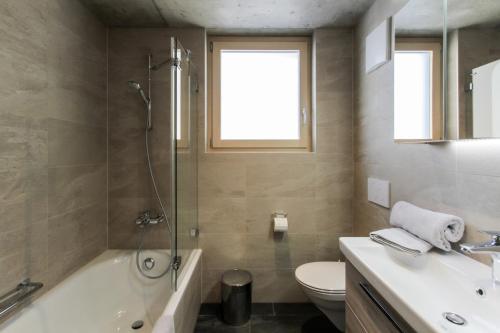 uma casa de banho com uma banheira, um WC e um lavatório. em House Mojo em Zermatt
