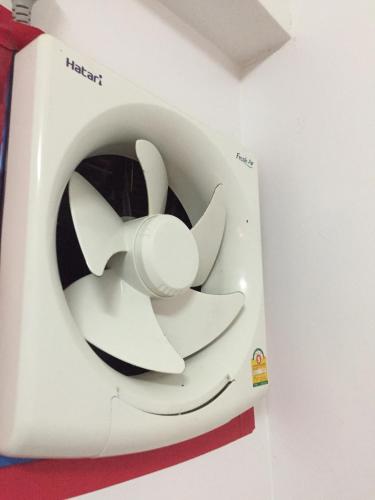 a washing machine with a white fan on a wall at Noot's Guesthouse in Kanchanaburi